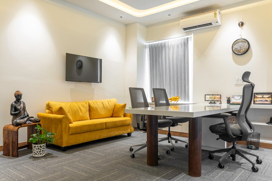 Stylish office space featuring a yellow sofa and Buddha decor in Sahibzada Ajit Singh Nagar.